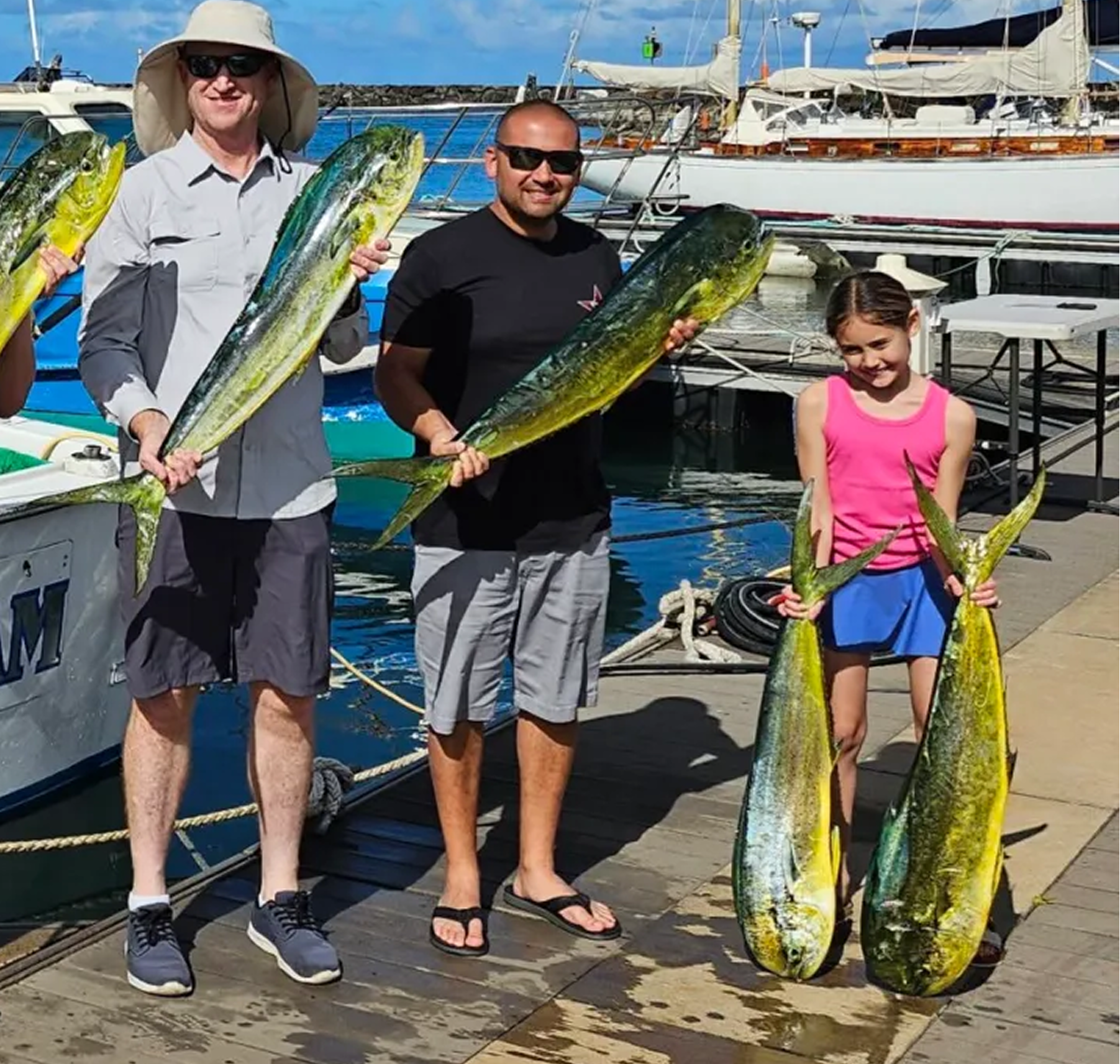 People holding large fish by a dock