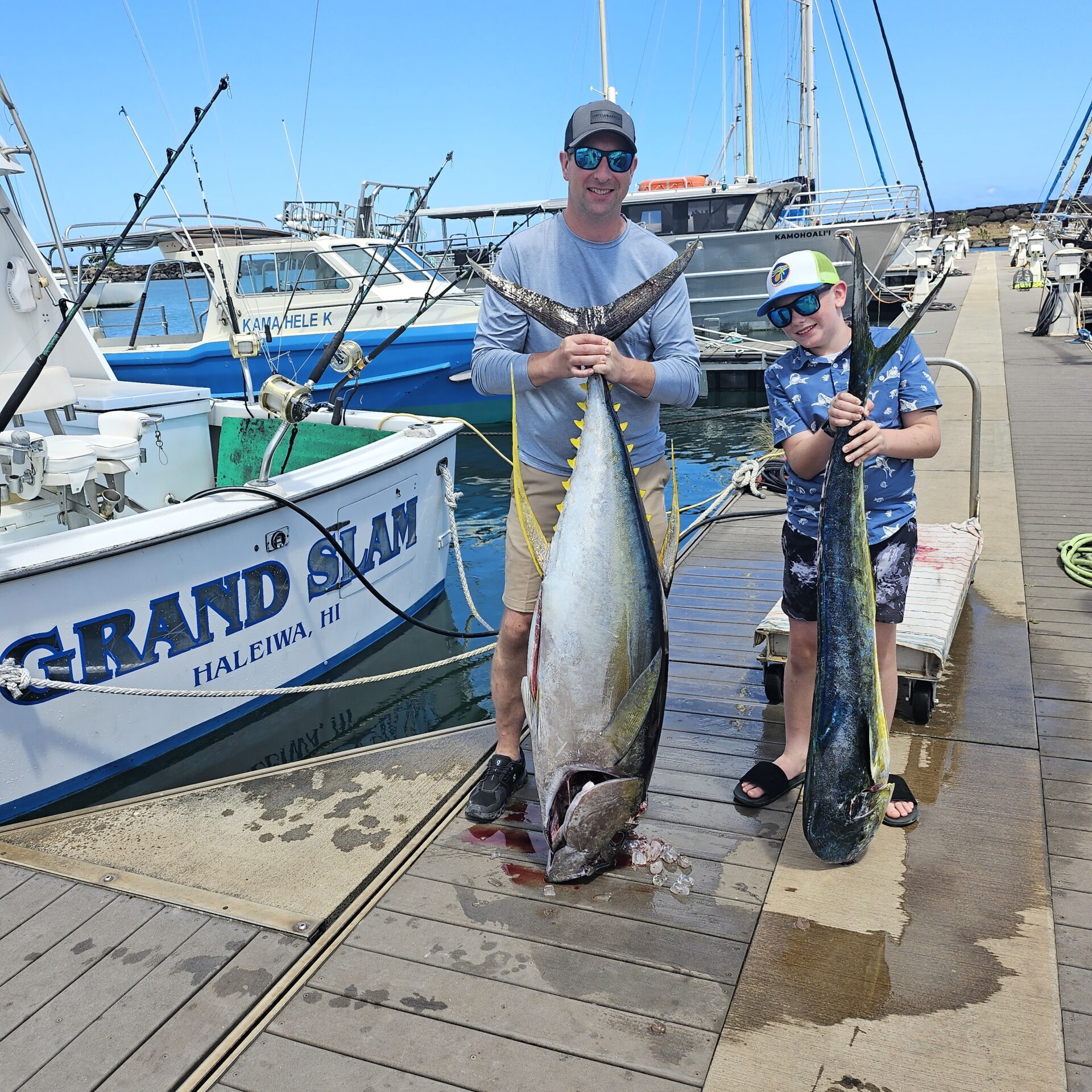 Two fishermen proudly display a large catch by the dock.